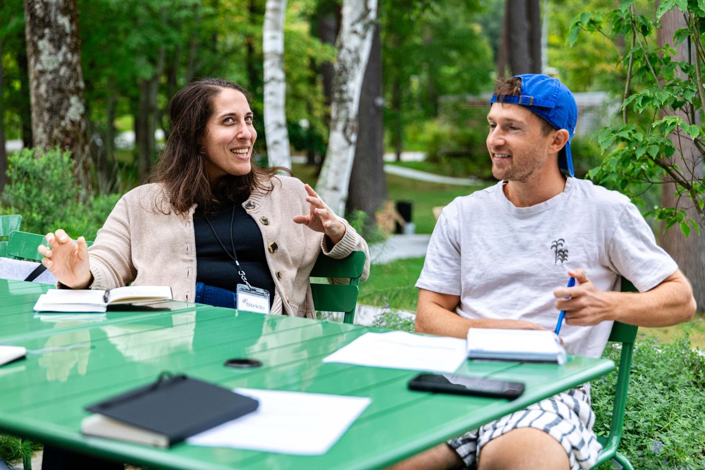 Two guests in conversation at green tables outside at the 2026 retreat
